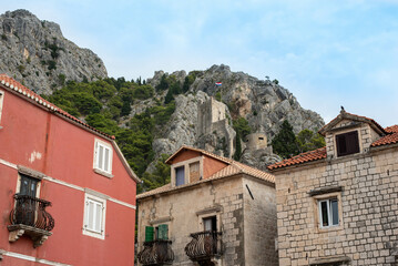 Fototapeta premium Fortress Peovica (Mirabela) overlooks Omis, Croatia, offering scenic views of the town, sea, and nearby mountains.