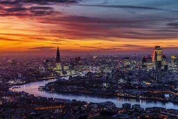 Fototapeta premium Elevated evening view of the illuminated London city skyline after a colorful sunset, England