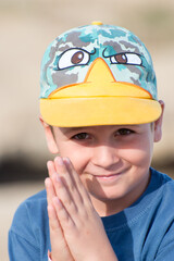 A cute little boy begging with a smile outdoors