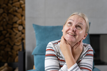 Middle-aged woman smiling and looking upward with a thoughtful and happy expression, sitting...