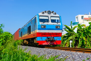 Freight train wagons container locomotive travels along the railway sunny day tropical jungle country