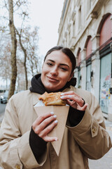 French woman eating delicious crepes in the streets of Paris city, hands holding traditional...