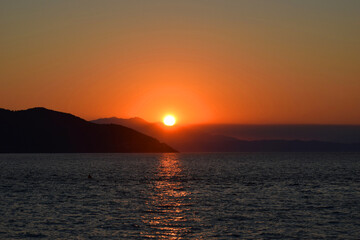 Breathtaking sunset over calm waters, with the golden glow reflecting on the sea surface.