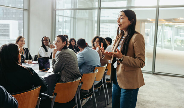 Female leader conducting a workshop with a group of professionals in a modern office space