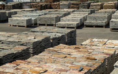 Warehouse with many pallets of gneiss stone slabs closeup