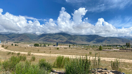 View of the stunning summer mountain landscape of Kyrgyzstan. A rural road to the mountains. White...