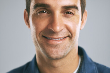 Man, face and happy in studio for positive attitude, confidence and pride with gray background. Male person, portrait and employee for creative agency, design and career growth with smile in Madrid