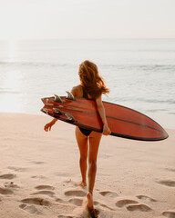 Woman with surfboard running on the beach to the ocean