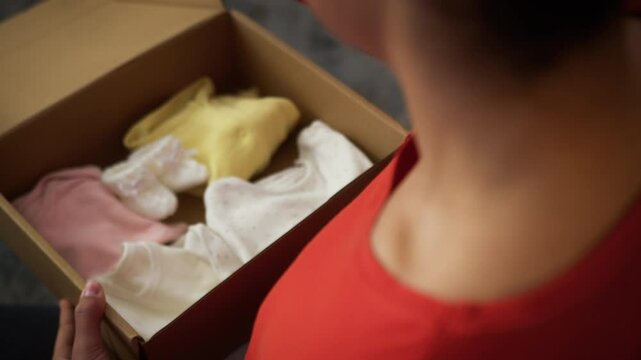 Pregnant woman African female girl lady mother pregnancy open cardboard parcel box order shopping online child kid clothes preparing to baby medicine holding little tiny baby shoes socks put on belly
