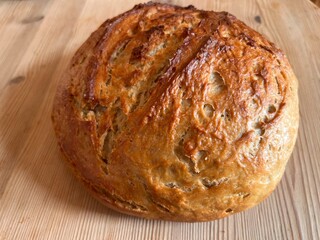 Close up of home made sour dough freshly home baked bread the wholemeal  delicious crusty loaf made with organic flour starter olive oil and water hot from oven on wood surface