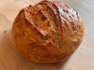 Close up of home made sour dough freshly home baked bread the wholemeal  delicious crusty loaf made with organic flour starter olive oil and water hot from oven on wood surface