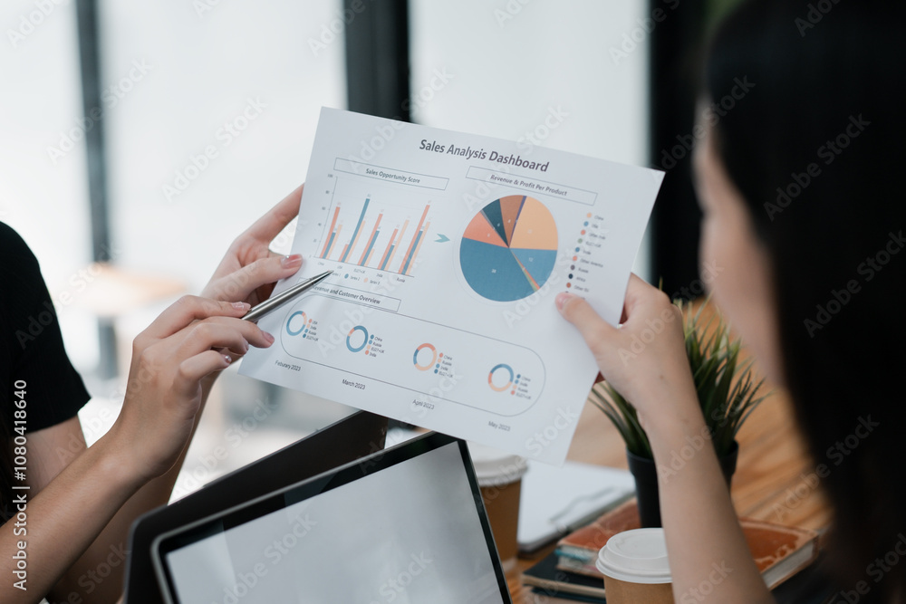 Poster two business professionals reviewing a sales analysis dashboard with charts and graphs in a modern o