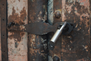 A metal padlock on the aged, rusty, abandoned metal gate. Old padlock, Door, Close up, Vintage style