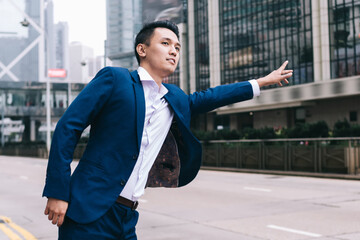 Stylish Asian businessman catching taxi on street