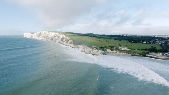 A beautiful ocean view with a white cliff in the background. The sky is clear and the water is calm