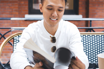 Asian man sitting with book in cafe