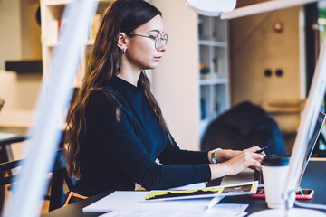 Millennial female copywriter typing text information during freelance work with web article for...