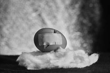 Broken egg shell with repair patch placed on a wadding cloud. Concept of fragility and resilience