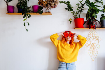 Woman in yellow sweater holding red flowers in stylish home