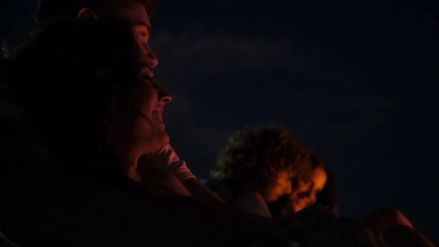 Group of friends dancing around fire on the beach