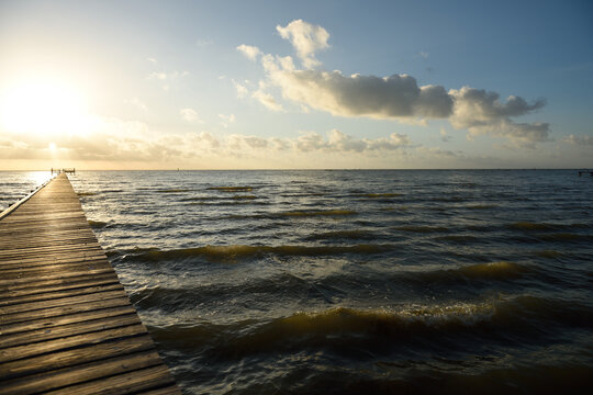 Long wooden pier over water leading to the sunrise and horizon on the Gulf of Mexico	