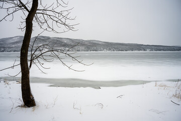 Moody winter scene by a snowy lake and a mountain