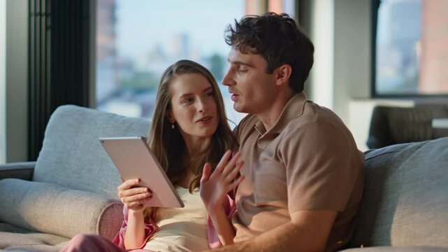 Joyful spouses shopping with tablet at home couch closeup. Happy couple enjoying