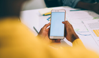 Faceless partner surfing smartphone during meeting