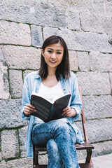 Asian modern woman reading book on street and smiling