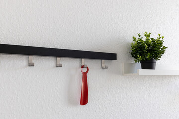 a red shoe horn on the wall and coat hooks in the dressing room.