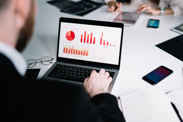 Man browsing laptop with charts on screen