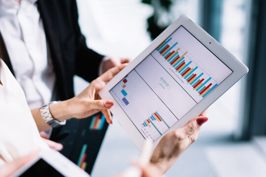 Group of office workers discussing financial statistics on tablet