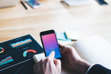 Crop businessman browsing smartphone in office