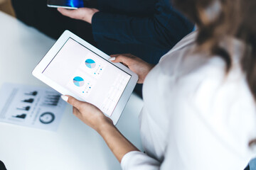 Female office worker using tablet with charts