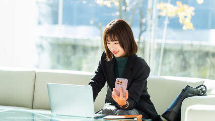 パソコンとスマホを使う女性・ビジネスウーマン