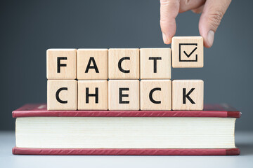 Hand arranging the alphabet wood blocks on the book, Fact Check concept