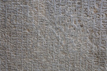 Archaeological Museum of Rhodes, Greece. Travel and history concept. Antique Greek text on stone tablets. Old cuneiform on a stones. Ancient inscription. Gray wall with historic letters.