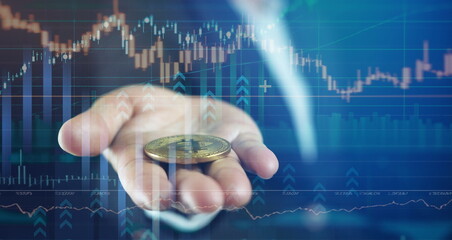 close up of hand holding physical Bitcoin coin, symbolizing cryptocurrency investment and market trends. background features digital financial chart.