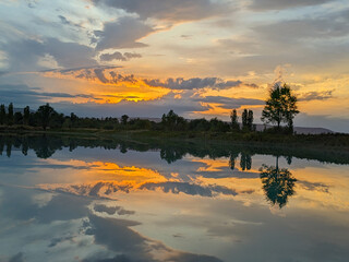 Lake, river, sea at sunset. Beautiful landscape of the shore of a pond with trees. Picturesque...