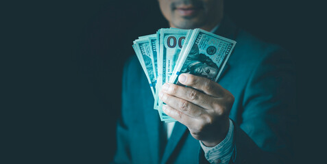 Businessman hand holding cash 100 dollar bills Business and finance concept, Saving money investment, Planning family budget, stock market, interest rate, Inflation, tax, long-term investment