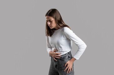 Woman has abdominal pain isolated on a gray background. Young woman suffering from stomach pain....