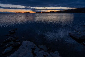 Stunning glowing orange sunset over the serene waters of 1000 Islands, capturing the vibrant colors reflected on the calm surface. Perfect for nature, travel, and scenic stock themes