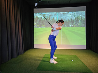 Professional female golfer holding club playing golf indoors on golf simulator concept