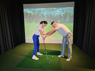 A golf instructor provides personalized guidance to a student in a high-tech indoor training facility, focusing on swing technique concept
