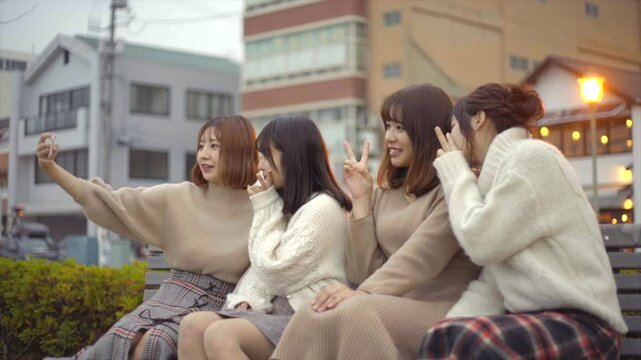 旅先のベンチで自撮りをする女性たち