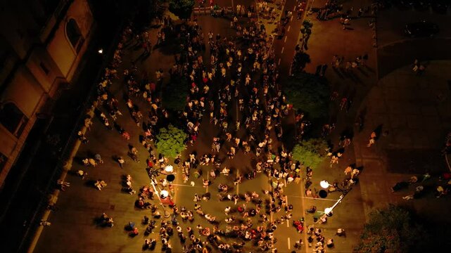 Aerial top down shot of crowds of people dancing in the streets at night. high angle drone footage of people street dancing salsa, bachata, west coast swing and tango seen from above. Open air music

