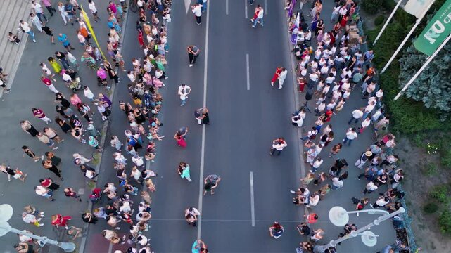 Aerial top down shot of crowds of people dancing in the streets. High angle drone footage of people street dancing salsa, bachata, west coast swing and tango seen from above. Open air music festival.

