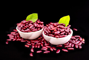 Raw red kidney beans in wooden bowl on black table, closeup