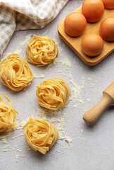 Tagliatelle nests with flour, eggs and rolling pin composing a beautiful food background