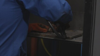 A man in a blue shirt is working with a piece of metal. Concept of focus and determination as the man uses a blowtorch to shape the metal - Powered by Adobe